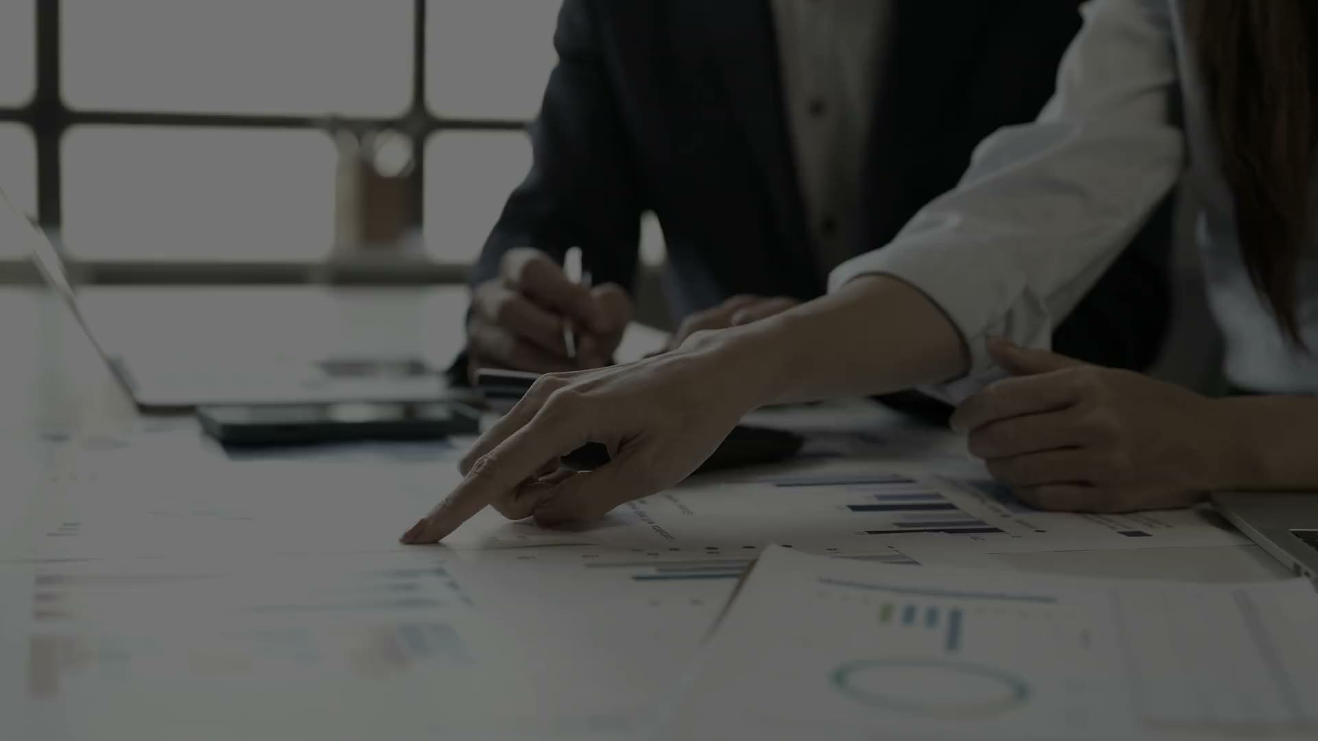 Two colleagues reviewing printed financial charts at a desk